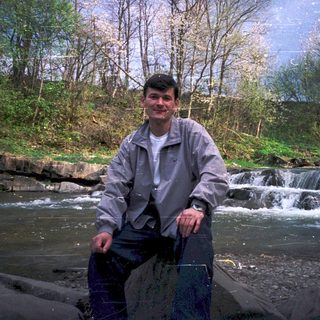 Man holding net by a flowing river with waterfall.