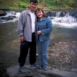Couple posing by a small waterfall in nature.