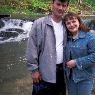 Couple posing by a small waterfall in nature.