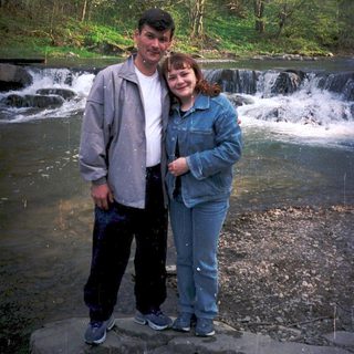 Couple posing by a small waterfall in nature.