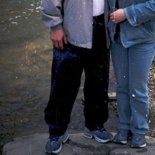 Couple posing by a small waterfall in nature.