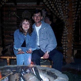 Two people sitting by a lit outdoor fire pit.