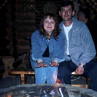 Two people sitting by a lit outdoor fire pit.