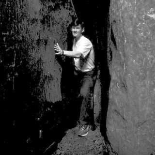 Person climbing or standing in narrow indoor rock climbing wall.