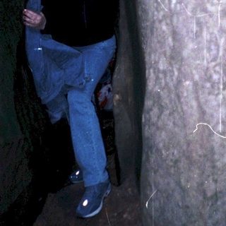 Person standing beside ancient carved rock wall.