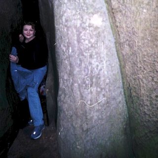 Person standing beside ancient carved rock wall.