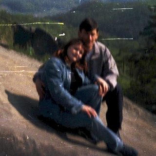 Two people sitting on rocky hillside at dusk.
