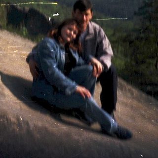 Two people sitting on rocky hillside at dusk.