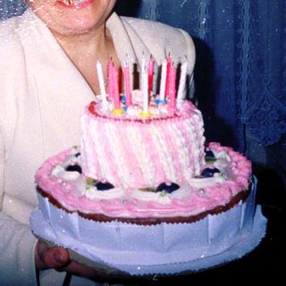 Woman holding birthday cake with lit candles.