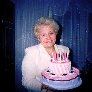 Woman holding birthday cake with lit candles.