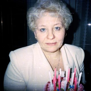 Woman in light blazer holding bouquet of flowers.
