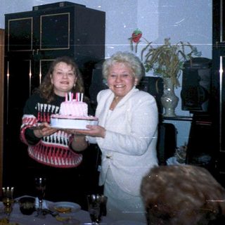 Family celebrating birthday indoors with cake.