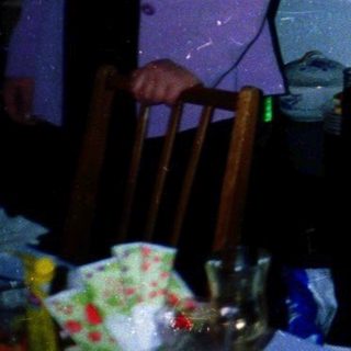 Elderly woman smelling rose at indoor celebration.