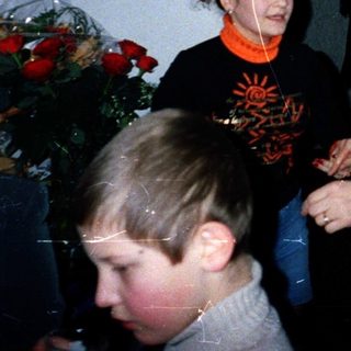 Family gathering indoors with elderly woman hugging young adult.