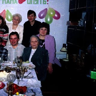 Family celebrating 45th birthday with balloons and cake.