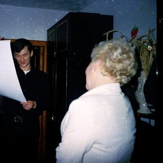 Man holding large rolled banner indoors with woman.