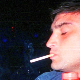 Man smoking while drinking near Coca-Cola bottle.