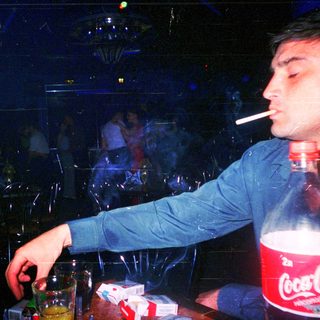 Man smoking while drinking near Coca-Cola bottle.