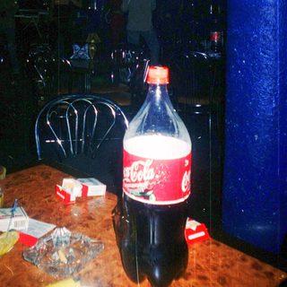 Kitchen scene with Coca-Cola bottle, empty glasses, and scattered items.