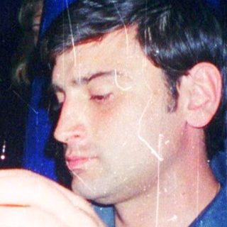 Man drinking soda indoors at a dimly lit table.