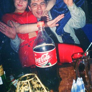Two people celebrating with soda bottle and confetti indoors.