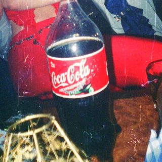 Two people celebrating with soda bottle and confetti indoors.