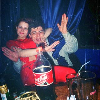 Two people celebrating with soda bottle and confetti indoors.
