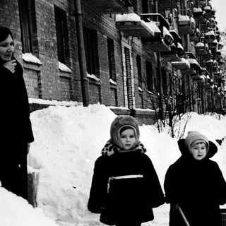 Two children walking in snowy urban street.