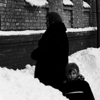 Snowy urban street with people shoveling snow.