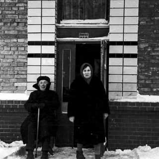 Two elderly individuals standing outside in winter snow.