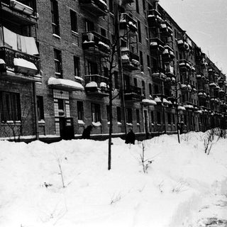 Snow-covered urban street with apartment buildings.