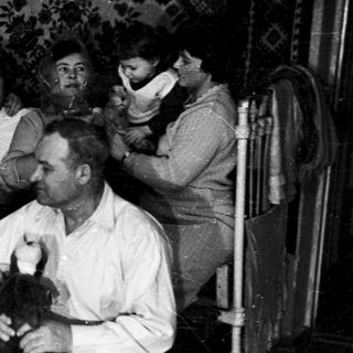 Group of men in a barber shop receiving haircuts.