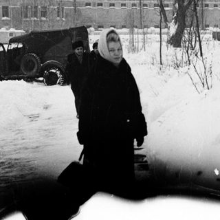 Person standing in snow near partially frozen puddle.