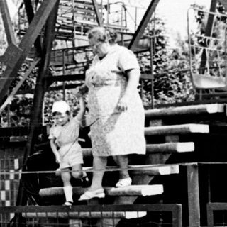 Family boarding amusement ride with Ferris wheel in background.