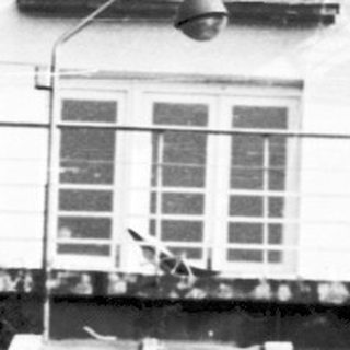 Black-and-white photo of people near a building entrance with steps and fountain.