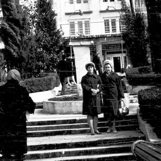 People standing outdoors near a building in winter attire.