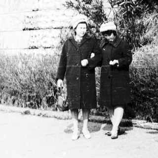 Two women walking outdoors on a paved path.