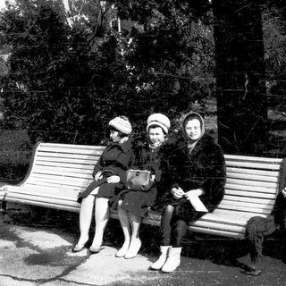 Three women sitting on a bench outdoors.