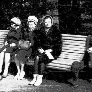 Three women sitting on a bench outdoors.
