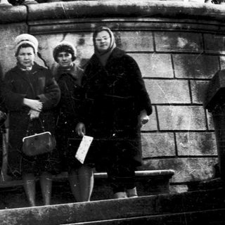 Four people posing on stone steps in vintage clothing.