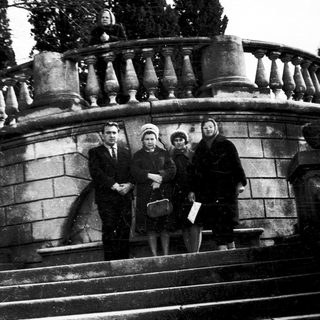 Four people posing on stone steps in vintage clothing.