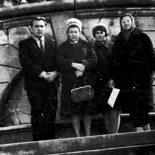 Four people posing on stone steps in vintage clothing.