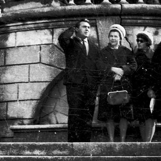 Four people posing on stone steps in a cemetery.