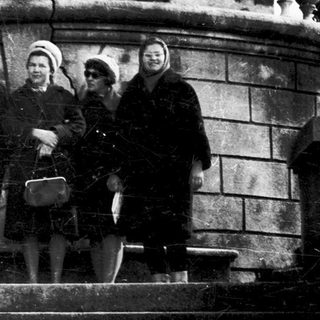Four people posing on stone steps in a cemetery.