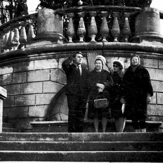 Four people posing on stone steps in a cemetery.