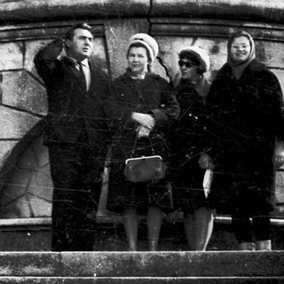 Four people posing on stone steps in a cemetery.
