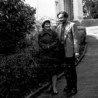 Two people posing outdoors in vintage attire.