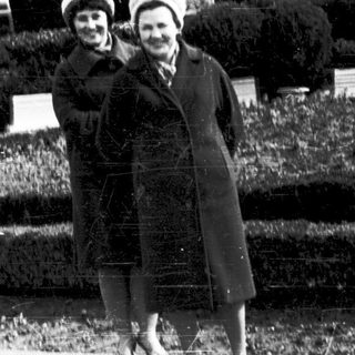Two women posing together outdoors in vintage clothing.