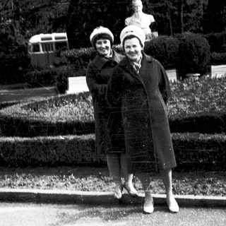 Two women posing together outdoors in vintage clothing.