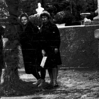 Four people posing outdoors near palm tree.